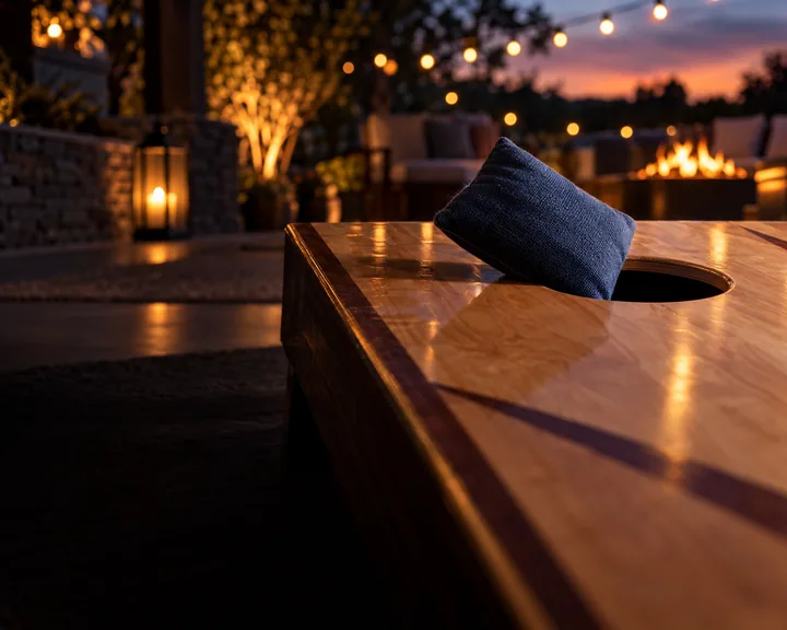 A bag sliding into the hole on a maple board at dusk